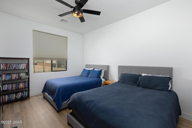 bedroom featuring visible vents, baseboards, a ceiling fan, and wood finished floors