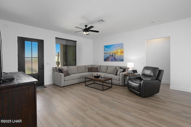living room featuring light wood-style flooring, ceiling fan, baseboards, and visible vents