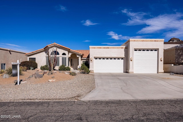 view of front of house featuring a garage, concrete driveway, a tiled roof, and stucco siding