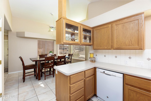 kitchen featuring tasteful backsplash, a ceiling fan, a peninsula, white dishwasher, and light countertops