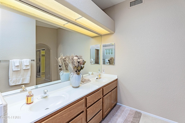 full bathroom featuring visible vents, a sink, baseboards, and double vanity