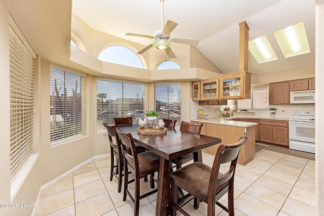 dining space featuring lofted ceiling, ceiling fan, baseboards, and light tile patterned flooring