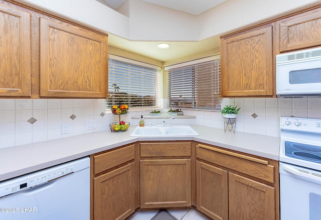 kitchen with light countertops, white appliances, backsplash, and a sink