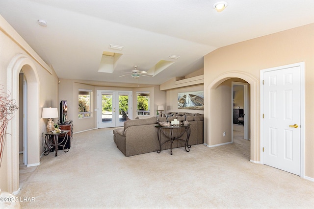 living room featuring arched walkways, french doors, vaulted ceiling, and light colored carpet