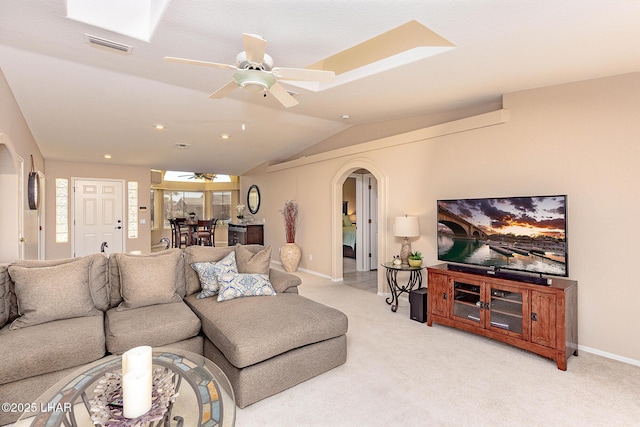 living area with arched walkways, ceiling fan, lofted ceiling, light colored carpet, and visible vents