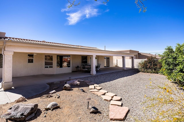 back of house featuring a patio area, a tiled roof, and stucco siding