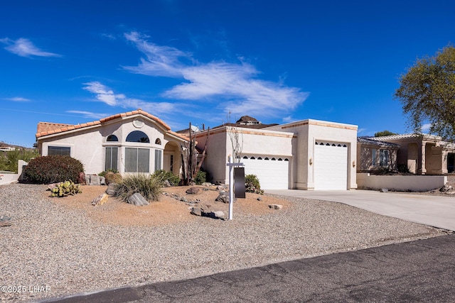 view of front of home with concrete driveway, an attached garage, a tile roof, and stucco siding