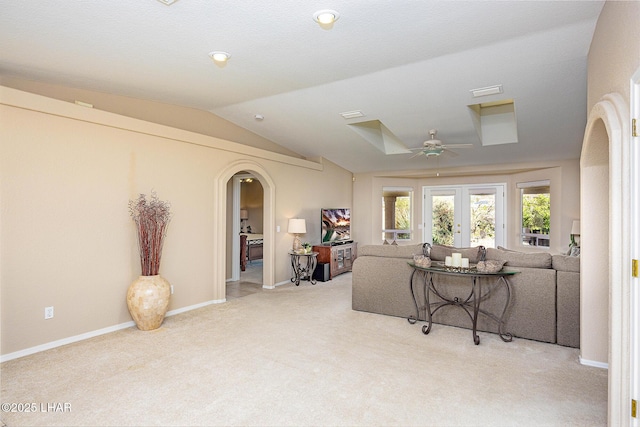 living area featuring arched walkways, carpet, a ceiling fan, vaulted ceiling, and baseboards