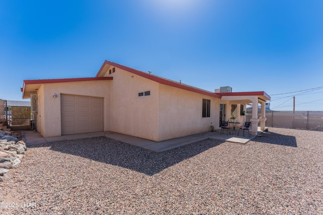 back of property with a patio area, an attached garage, fence, and stucco siding