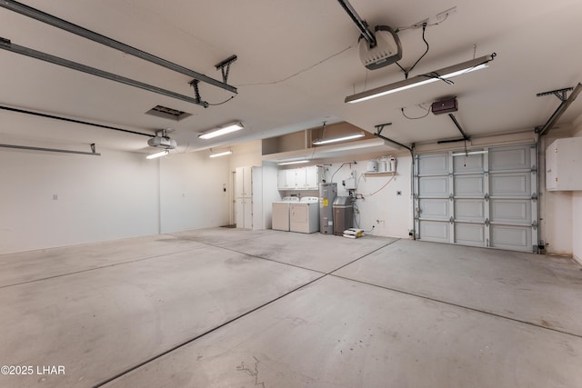 garage with a garage door opener, electric water heater, and washing machine and clothes dryer