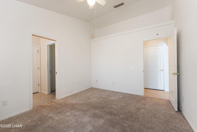 carpeted empty room with tile patterned floors, visible vents, and ceiling fan