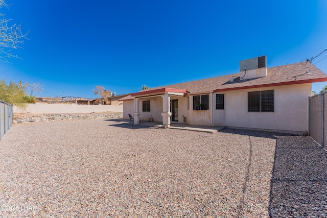 rear view of property featuring a patio, central AC unit, a fenced backyard, and stucco siding