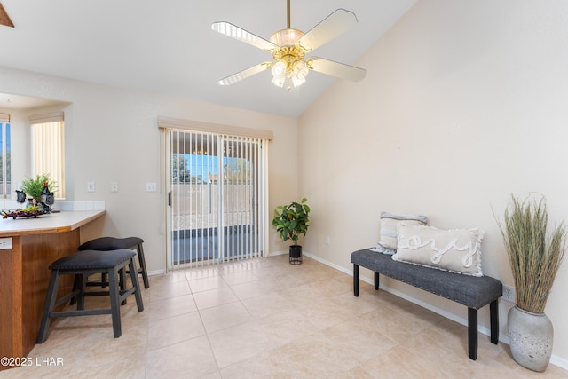 living area with light tile patterned floors, ceiling fan, baseboards, and lofted ceiling