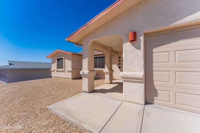 exterior space with a patio area, a garage, and stucco siding