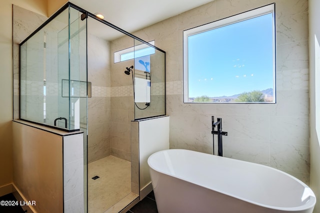 bathroom with tile walls and shower with separate bathtub