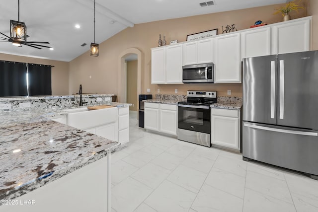 kitchen with hanging light fixtures, vaulted ceiling with beams, stainless steel appliances, light stone countertops, and white cabinets