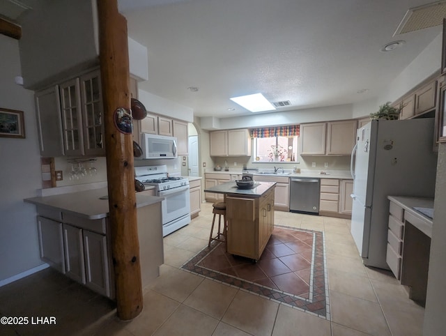 kitchen with a sink, white appliances, a breakfast bar, and light tile patterned flooring