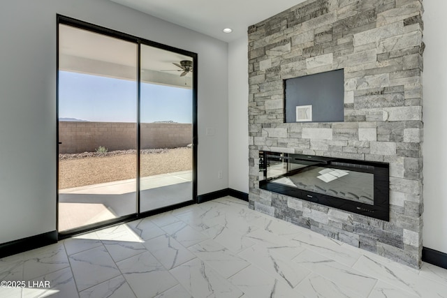 unfurnished living room with ceiling fan, marble finish floor, a fireplace, and baseboards