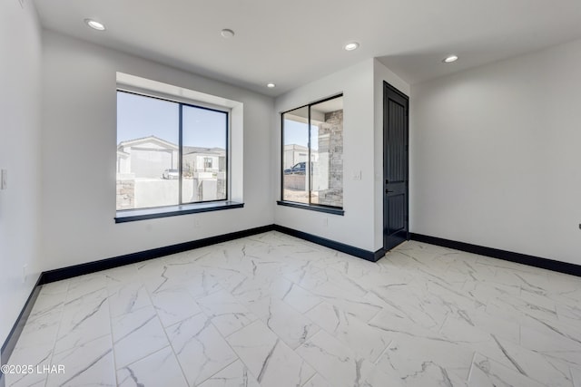 empty room with marble finish floor, baseboards, and recessed lighting