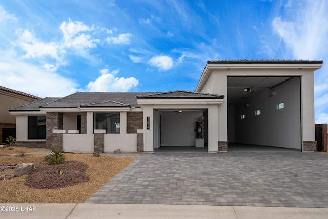 view of front of property with a garage, stone siding, decorative driveway, and stucco siding