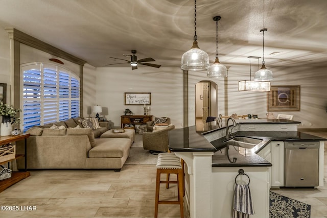 kitchen with decorative light fixtures, white cabinetry, dishwasher, sink, and a kitchen breakfast bar