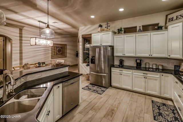 kitchen with sink, light hardwood / wood-style flooring, stainless steel appliances, white cabinets, and decorative light fixtures