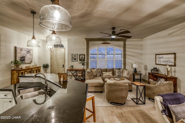 living room featuring sink, light hardwood / wood-style floors, and ceiling fan