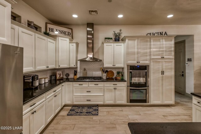 kitchen with stainless steel appliances, decorative backsplash, and wall chimney exhaust hood