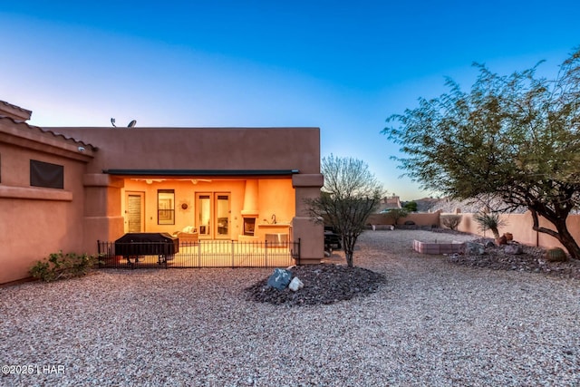 back house at dusk featuring a patio