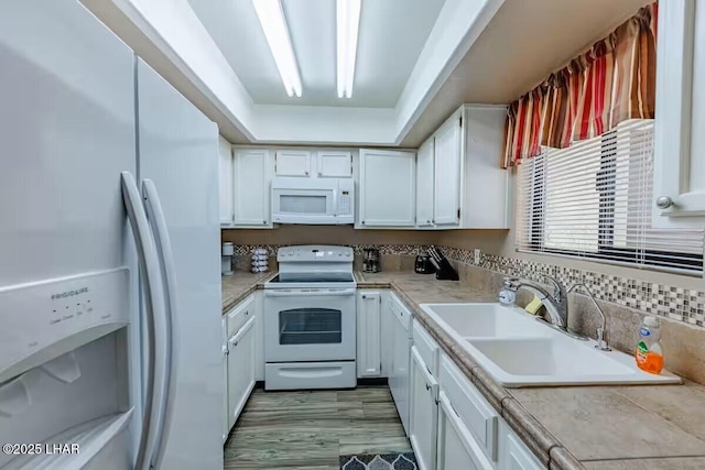 kitchen featuring white appliances, sink, white cabinets, and tile counters