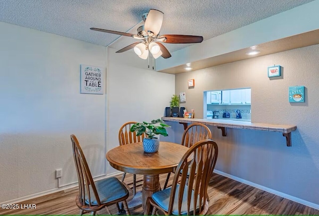 dining room with a textured ceiling, ceiling fan, and light hardwood / wood-style floors