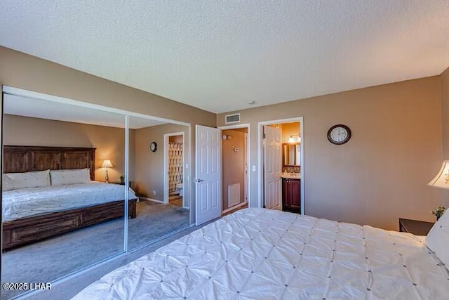 unfurnished bedroom featuring ensuite bathroom, carpet floors, and a textured ceiling