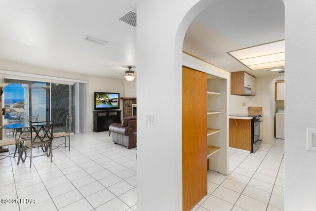 interior space featuring washer / clothes dryer, ceiling fan, and light tile patterned flooring