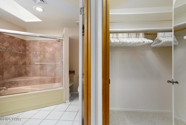 bathroom featuring tile patterned flooring, shower / bath combination with glass door, and a skylight