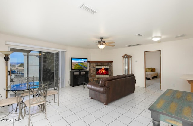 tiled living room featuring ceiling fan and a fireplace