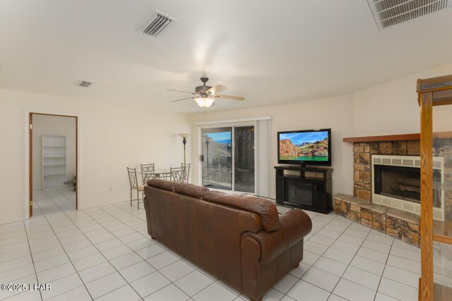 living room featuring light tile patterned floors, a fireplace, and ceiling fan