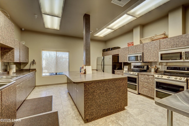 kitchen with a center island, visible vents, appliances with stainless steel finishes, a sink, and modern cabinets