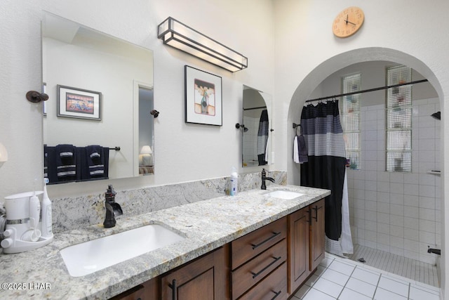 full bath featuring double vanity, a tile shower, a sink, and tile patterned floors