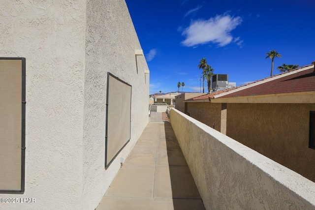 view of property exterior with central air condition unit, fence, a gate, and stucco siding