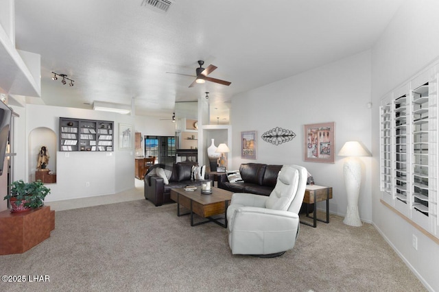 living area with carpet, rail lighting, visible vents, and a ceiling fan