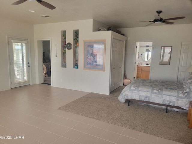 unfurnished bedroom with connected bathroom, carpet flooring, a ceiling fan, visible vents, and tile patterned floors