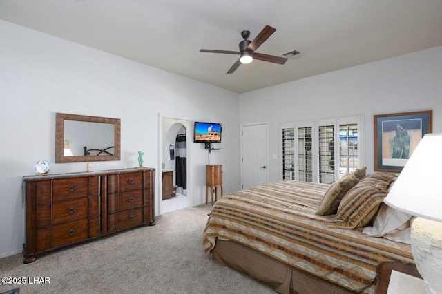 bedroom featuring arched walkways, light colored carpet, connected bathroom, and visible vents