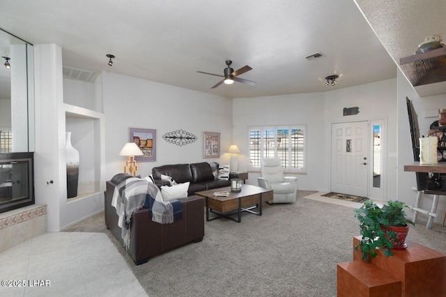 carpeted living area with a ceiling fan, visible vents, and tile patterned floors