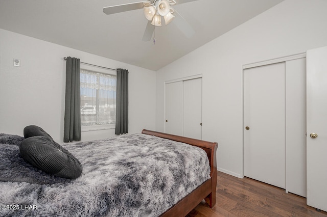 bedroom featuring dark wood-type flooring, ceiling fan, vaulted ceiling, and two closets