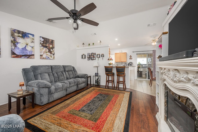 living room with dark wood-type flooring, ceiling fan, and vaulted ceiling