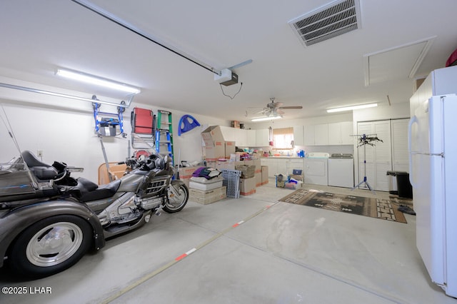 garage featuring white refrigerator, a garage door opener, and washing machine and clothes dryer