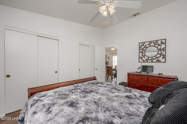 bedroom featuring wood-type flooring, two closets, and ceiling fan