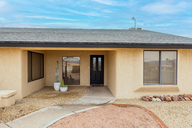 property entrance featuring a shingled roof and stucco siding