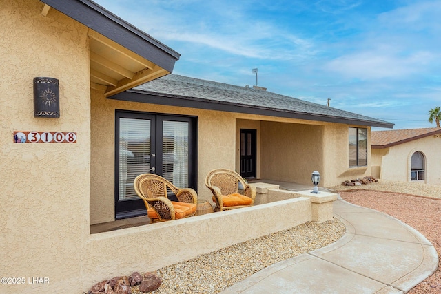 rear view of property featuring a shingled roof and stucco siding