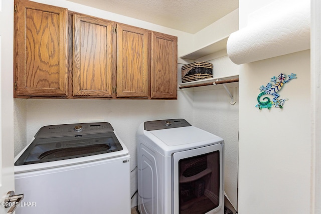 laundry room with a textured ceiling, washer and clothes dryer, and cabinet space